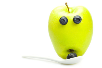 green apple with eyes of blueberries isolated on white