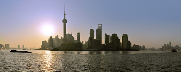 Fototapeta premium The sun rises behind the skyline of Shanghai's Pudong district