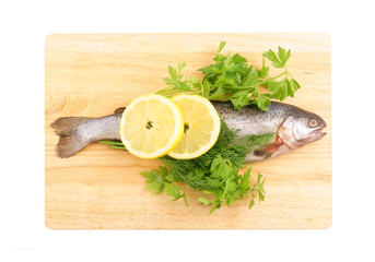 Raw fish with lemon and parsley on chopping board isolated