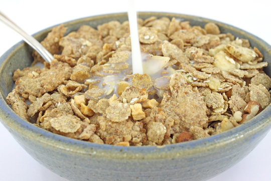 Banana and nut granola cereal with milk pouring