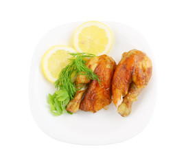 Roasted chicken with lemon and greens on plate isolated