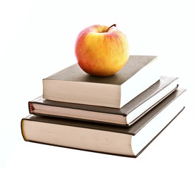Three books and apple isolated on white