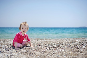 Fototapeta na wymiar Cute toddler girl playing on a beach