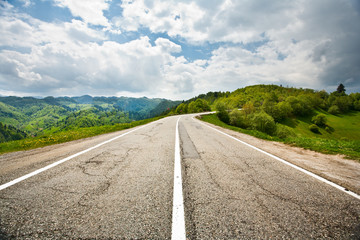 Landscape with empty road and trees under cloudy sky