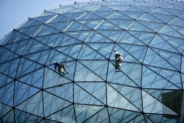 Climber cleaning mirror glass dome building climbing ropes