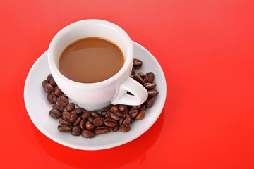 Small white cup of coffee with coffee grain on red background