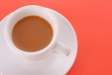 Small white cup with coffee on red background