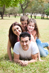 Fototapeta premium Happy family lying in the grass field at the park