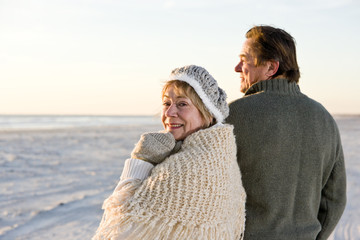 Affectionate senior couple in sweaters on beach