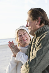 Senior couple in sweaters together on beach
