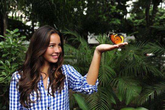 butterfly sitting on the hand of a young woman in the forest