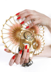 Beautiful hand with perfect red manicure holding carnival mask.