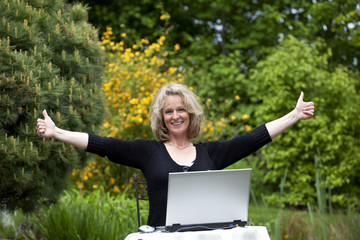 glückliche hübsche blonde Frau mit Laptop in Siegerpose