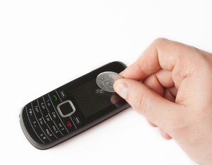 Mobile phone with coins in human hand.
