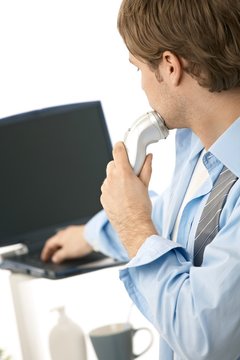Man using laptop while shaving