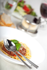 Teller mit Spaghetti Bolognese und Basilikumblatt