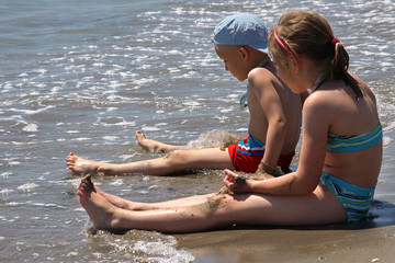Chłopiec i dziewczynka siedzą na plaży © wideonet