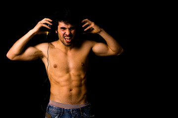 Young Man listening to music with headphones, on black backgroun