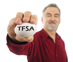 Mature man holds a white nest egg with TFSA on it.