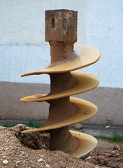 The metal drill is twisted in the earth
