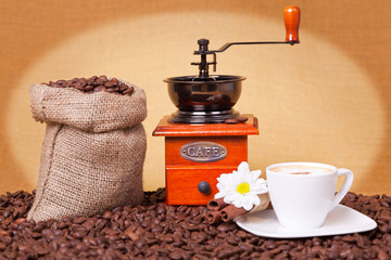 Coffee cup with grinder and burlap sack on roasted beans