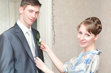 Young woman helps man to wear a suit