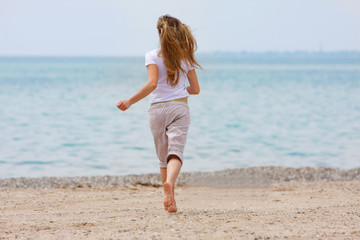 young girl running away on beach