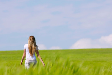 Fototapeta na wymiar young girl going away in green field