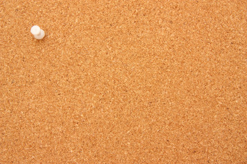 Single white pushpin on corkboard