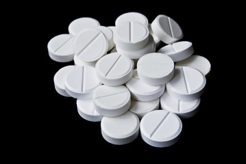Pile of the white pills on the black background