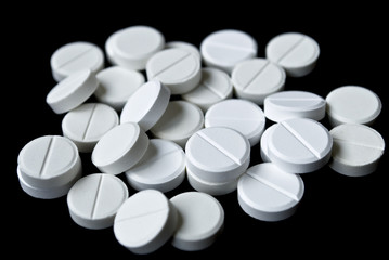 Scattering of white tablets on black background