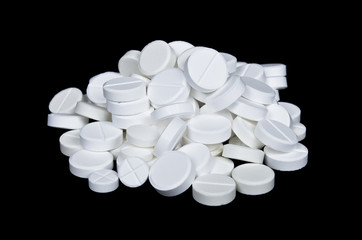Pile of the white pills on the black background