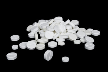 White pills scattered on the black background
