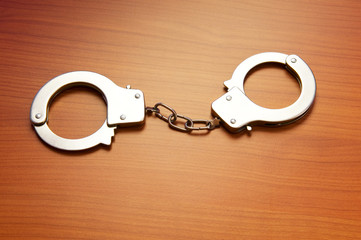 Metal handcuffs on the wooden background