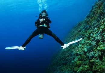 female scuba diver swimms backwards