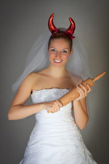 Bride in wedding dress wearing devil horns
