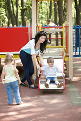Fototapeta na wymiar Mother with children on slide outdoor.