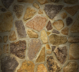 Masonry wall with irregular stones lit from above