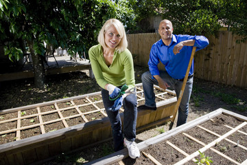 Couple working on vegetable garden in backyard