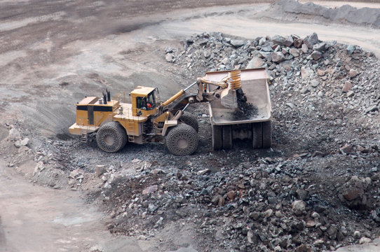 An Excavator Loading a Lorry Truck in a Granite Quarry.