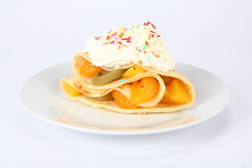 Pancake stuffed with fruit with whipped cream and sprinkles