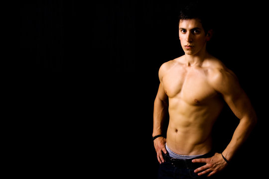 Young man with atletic body on black background