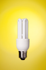 Small energy saving lamp on yellow background