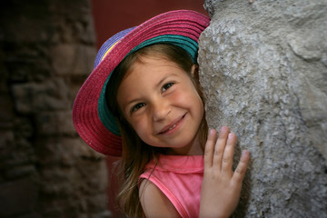 Pretty young girl looking around a corner and smiling
