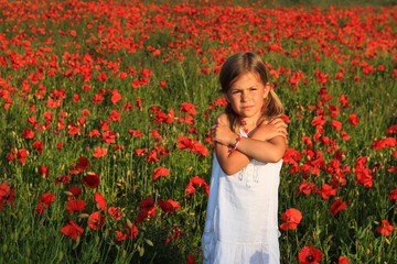 Pretty young girl standing in a poppy field