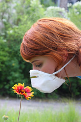 girl smelling flower through protective mask