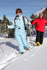 Homme et femme seniors se promenant en raquettes à la neige