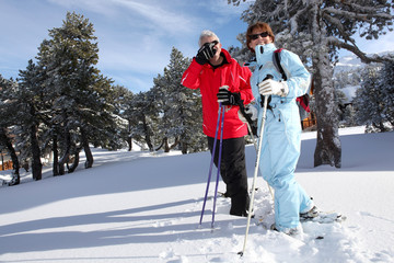 Homme et femme seniors se promenant en raquettes à la neige