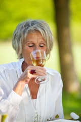 ältere frau trinkt weißwein