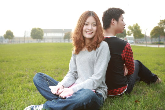 couple of asina reading book on grass